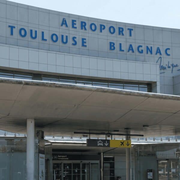 Entrada principal del aeropuerto Toulouse Blagnac en Francia, con señalización y acceso peatonal vis.