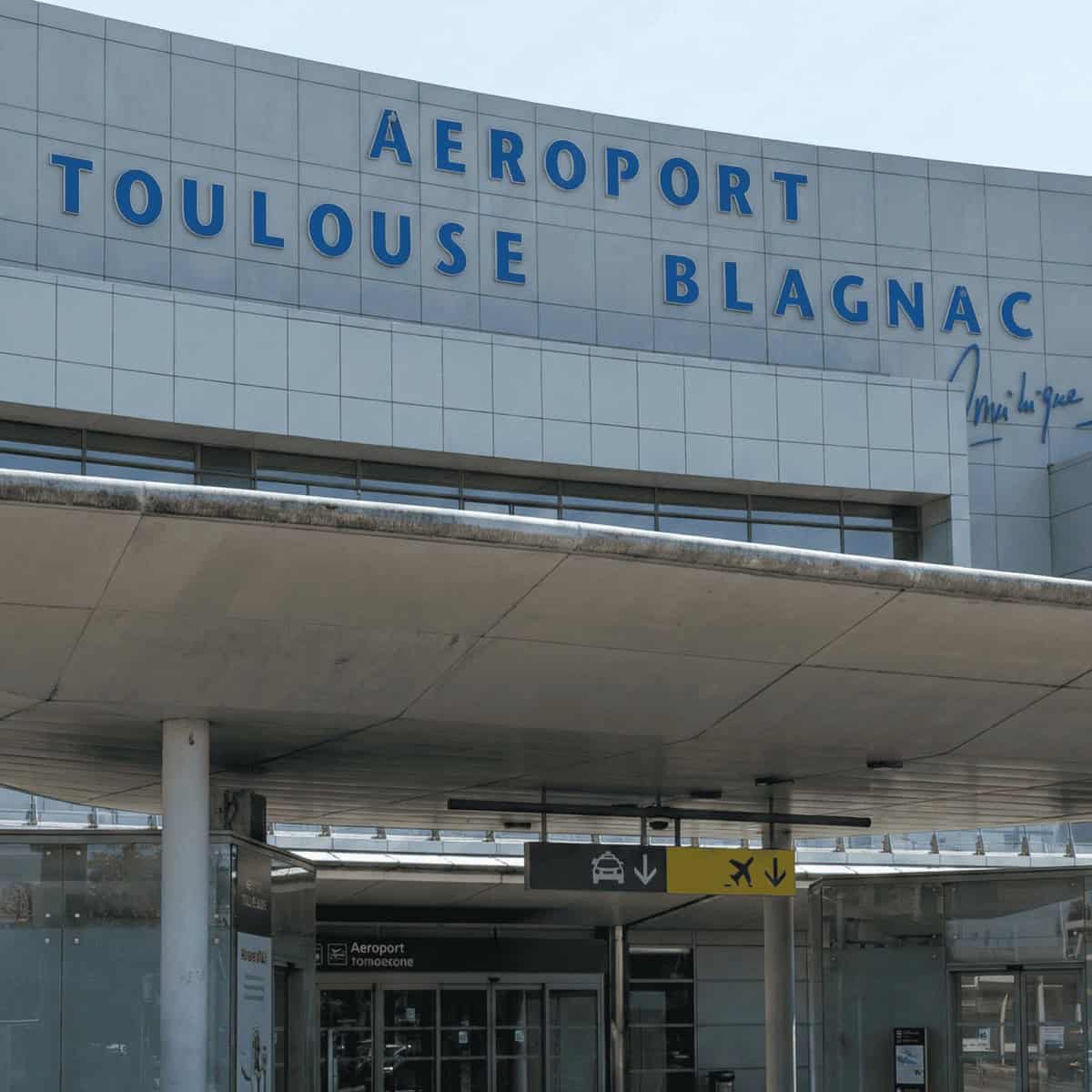Entrada principal del aeropuerto Toulouse Blagnac en Francia, con señalización y acceso peatonal.